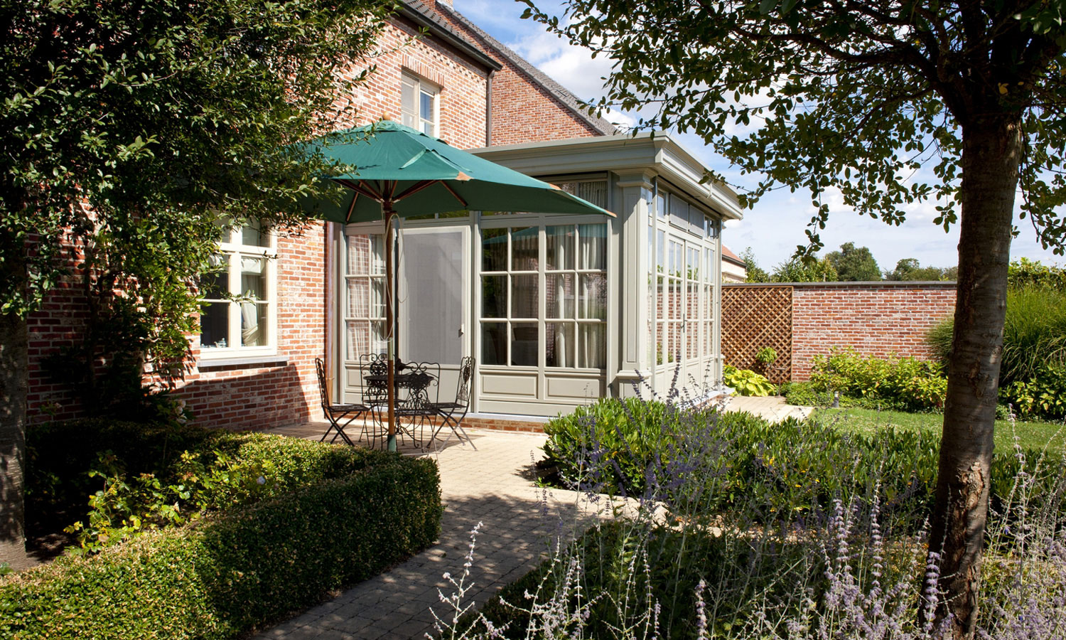  Gemütliche Gesbo Veranda aus Holz in Mülheim an einem Backsteinhaus mit Terrasse, Sonnenschirm und Blick in den grünen Garten. 