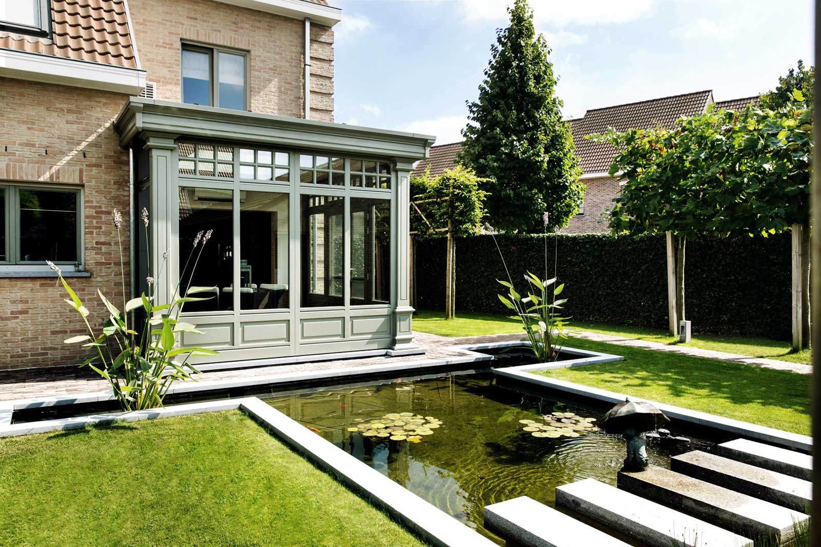  Klassische Holzveranda in Mülheim mit Sprossenfenstern an einem Backsteinhaus, angrenzend an einen malerischen Garten mit Teich. 