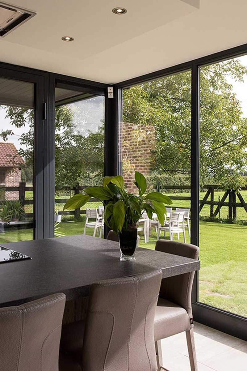 Moderner Wintergarten mit schwarzem Rahmen an einem weißen Backsteinhaus in Mülheim. Herbstliche Atmosphäre.