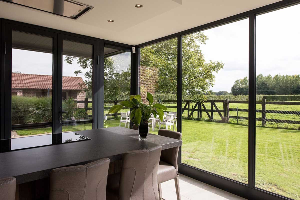 Moderner Wintergarten mit Ausblick auf Garten mit schöner Weide.