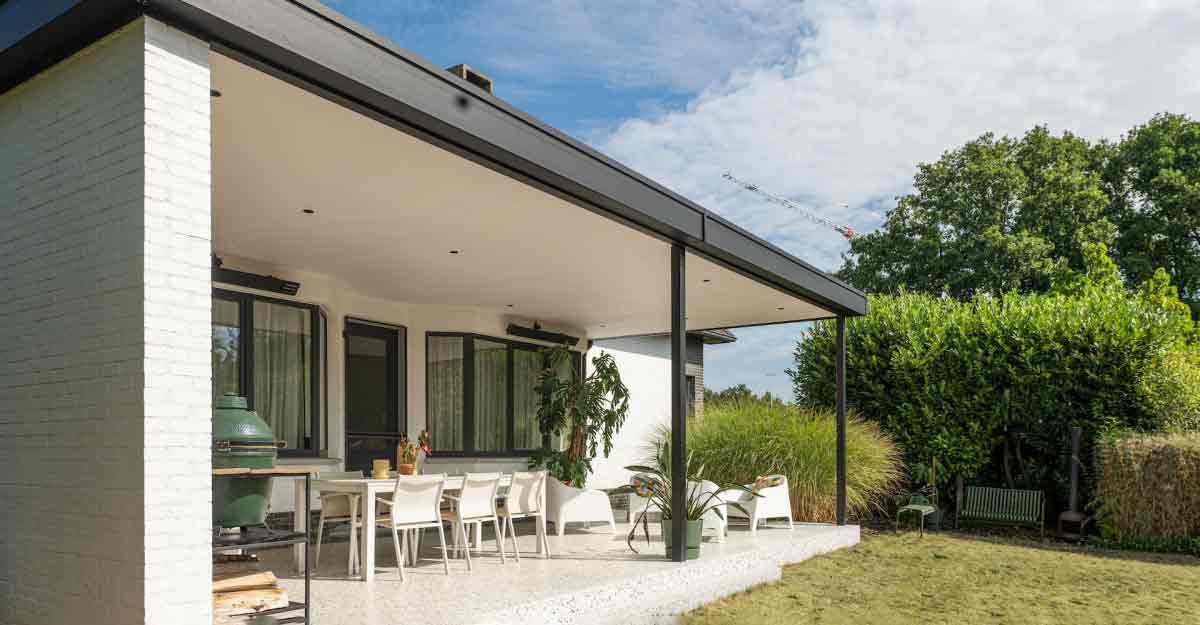 Moderne Pergola in Mülheim mit schwarzem Rahmen, weißem Dach und Essbereich im Freien. Grüner Garten und blauer Himmel.