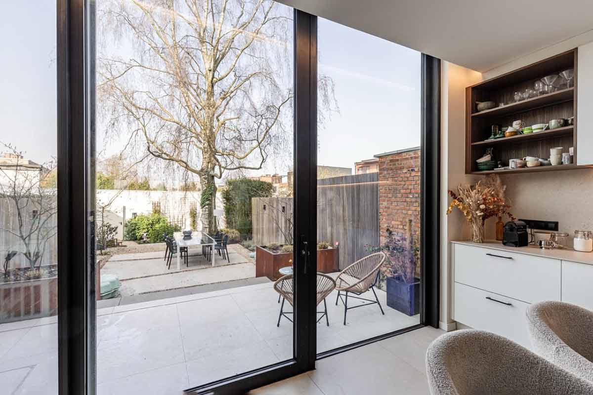 Große Schiebetür aus Aluminium verbindet die Küche mit Terrasse und Garten