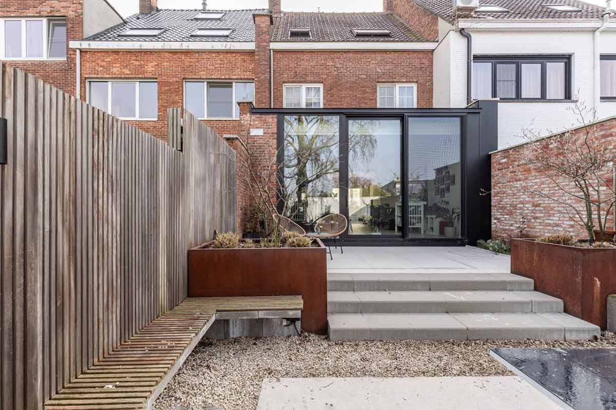Außenansicht des modernen Anbaus mit bodentiefen Fenstern und Terrasse