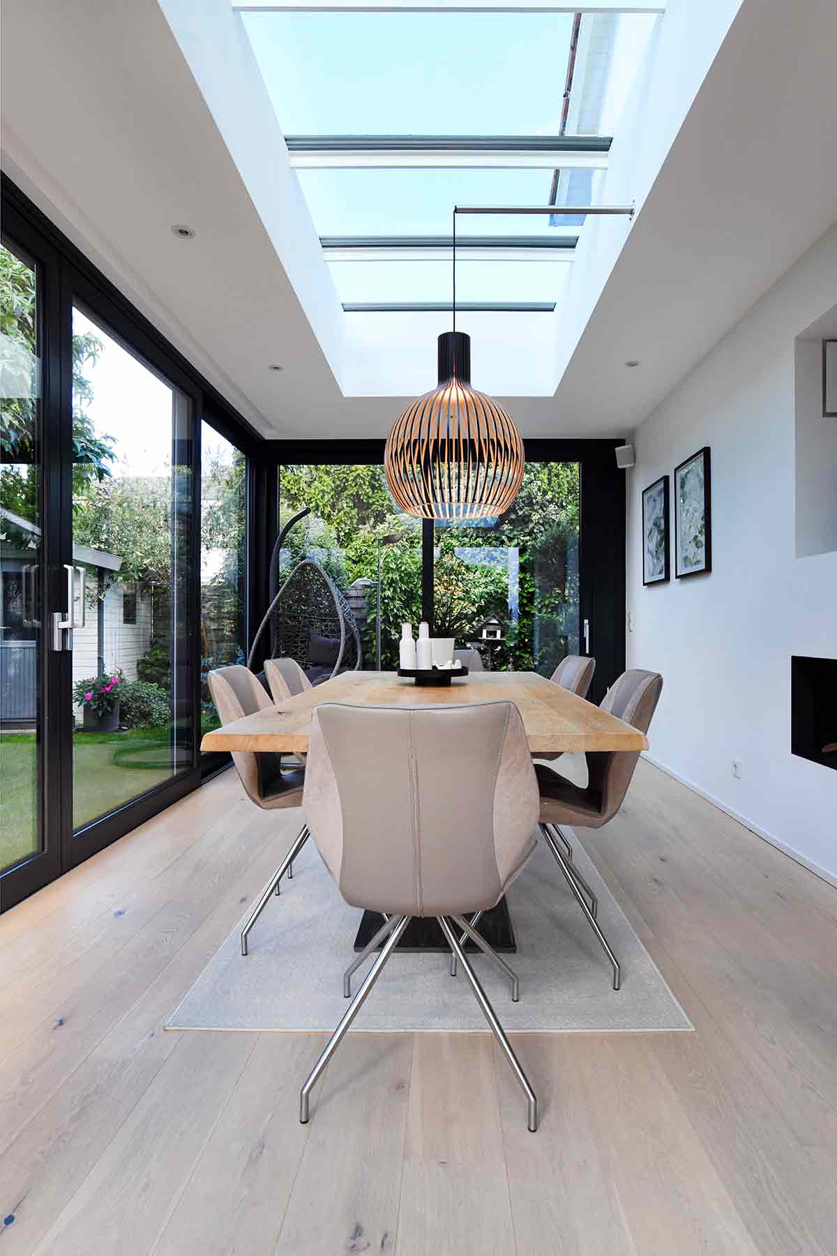 Luminöser Wintergarten-Essbereich in Mülheim mit langem Holztisch, modernen Stühlen, Designleuchte und großem Oberlicht.